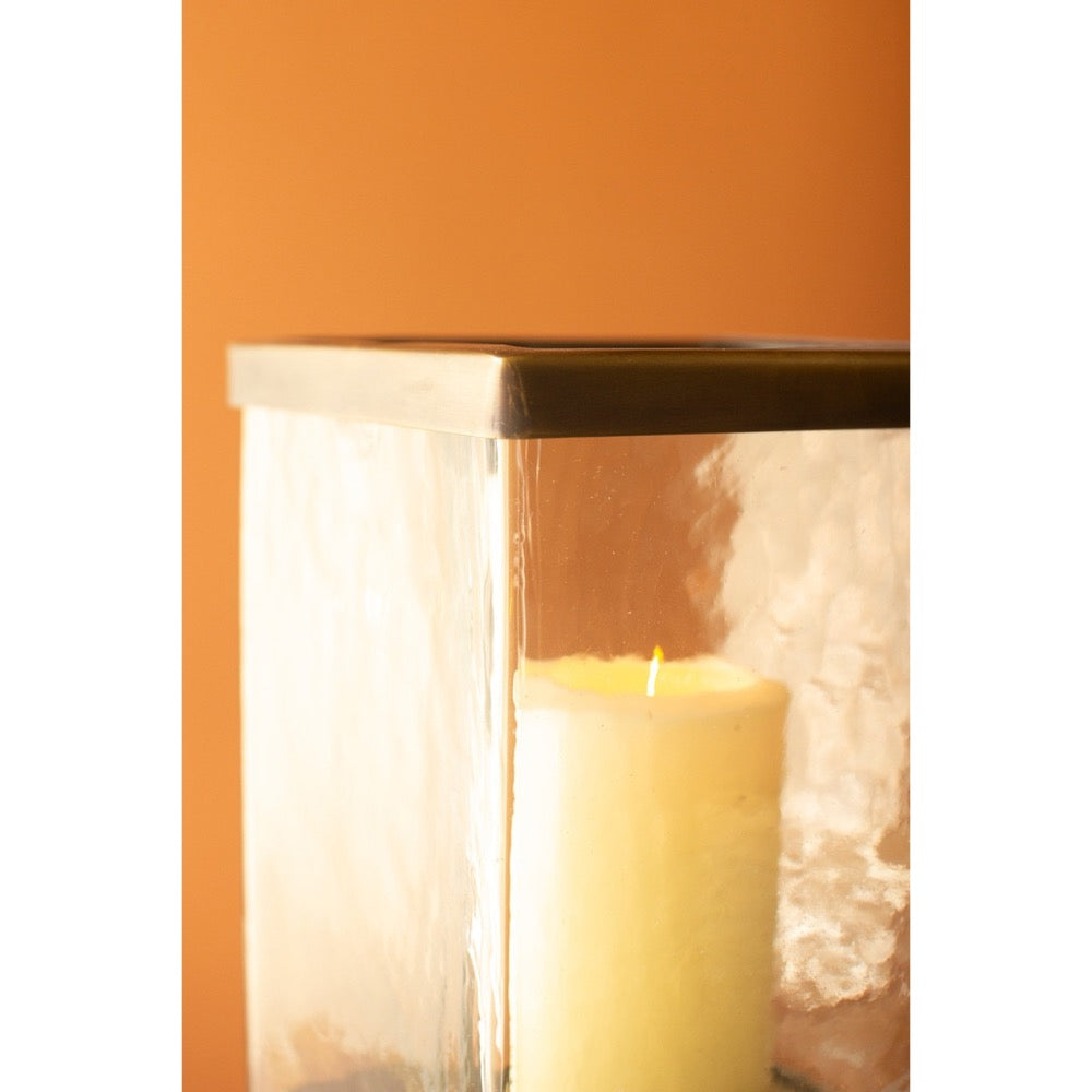 Candle in a glass lantern with lace details against an orange background