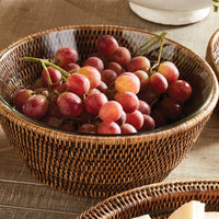 Wicker bowl filled with red grapes on a wooden table