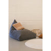The Big Puff Emily Grey Floor Cushion by Lorena Canals with a brown pillow beside a basket and round beige rug.
