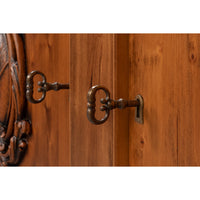Close-up of a warm brown wooden cabinet door with two ornate antique-style metal keyhole pulls mounted on the wood.