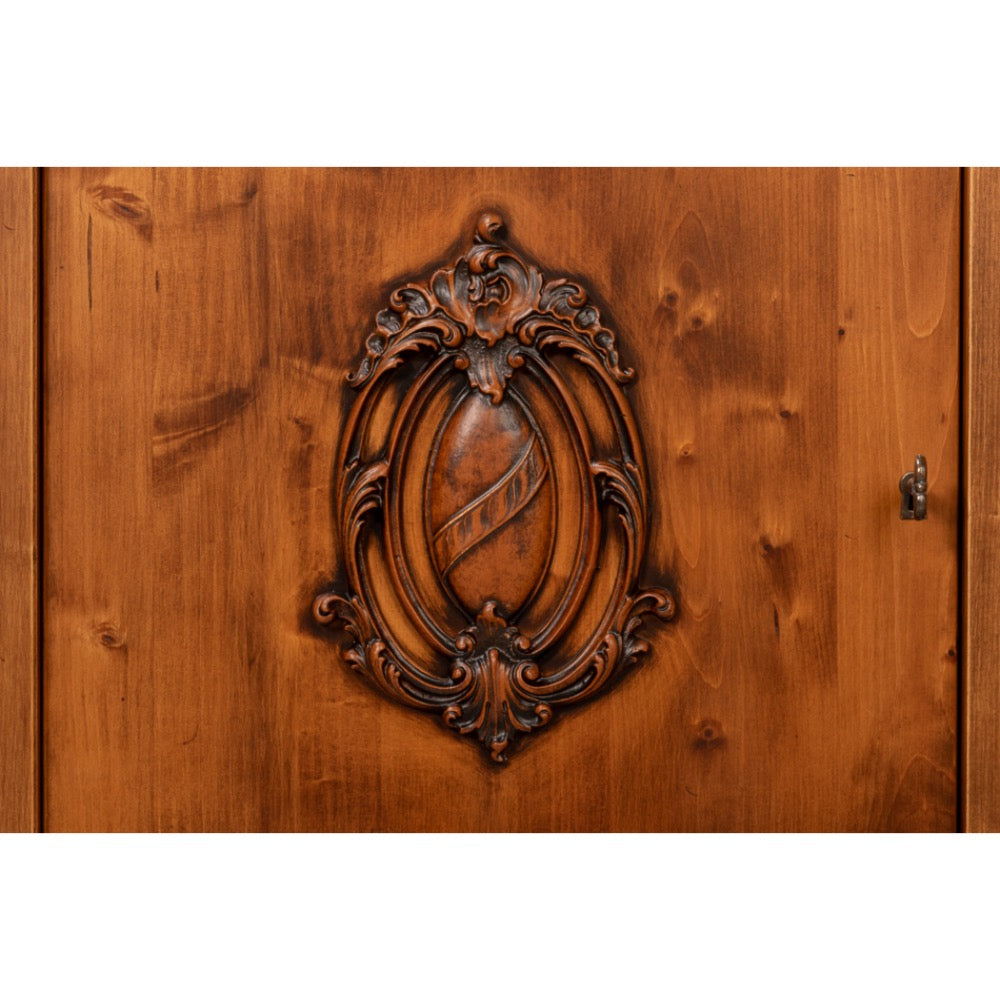 Close-up of a carved wooden cabinet door featuring an ornate oval crest inlaid into warm brown wood grain.