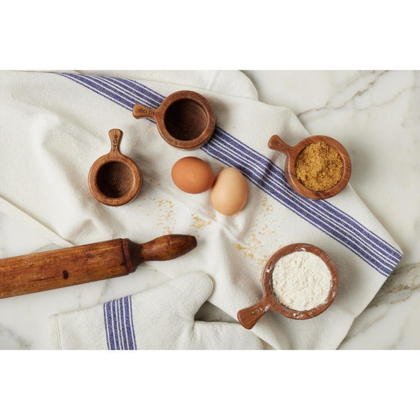 Two eggs, flour, brown sugar, and ETU Home French Bistro Wood Measuring Cups on a towel with a rolling pin on marble.