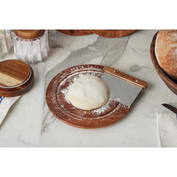 Wooden bench scraper with dough on a marble surface