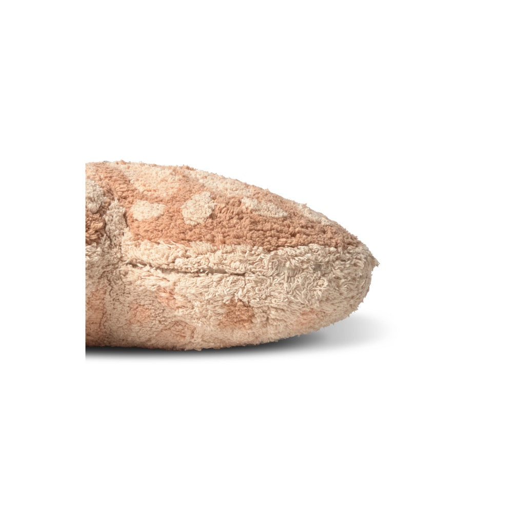 A close-up of a textured, plush throw pillow in a warm beige and light brown color, showing its soft, fuzzy fabric surface and rounded triangular shape against a plain white background.