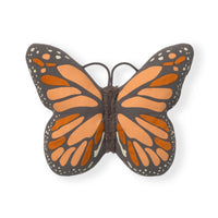 A butterfly-shaped decorative cushion with dark gray wings, orange and peach wing patterns, and small white dots, shown on a plain white background.