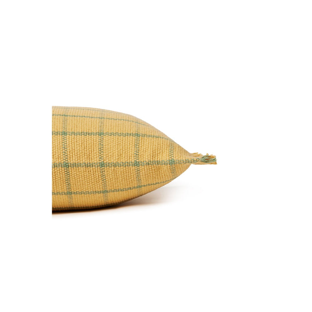 A close-up side view of a woven throw pillow in a mustard yellow color with a green plaid pattern, showing the textured fabric and a frayed edge, set against a plain white background.