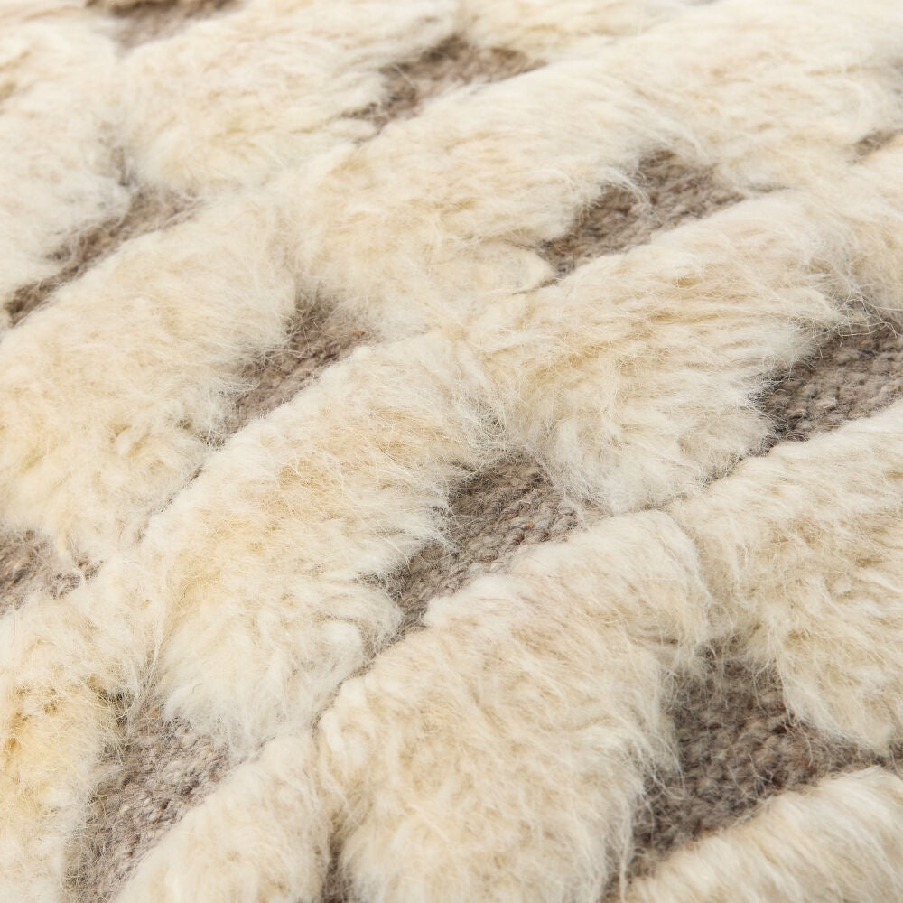 Close-up of a textured woven pillow with thick, fluffy cream-colored material over a taupe-brown base.