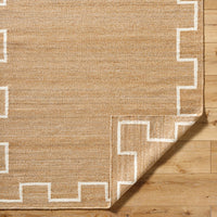 Beige rug with white geometric border on wooden floor