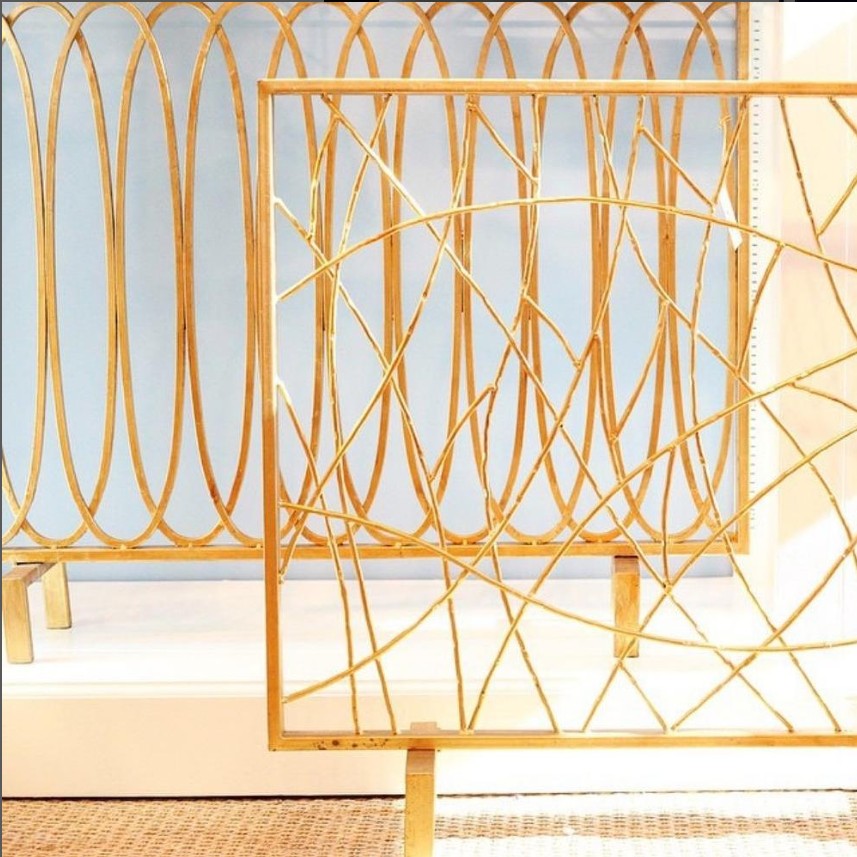 Dessau Home's Antique Gold Oval Loop Fireplace Screen casts abstract shadows on a light floor.