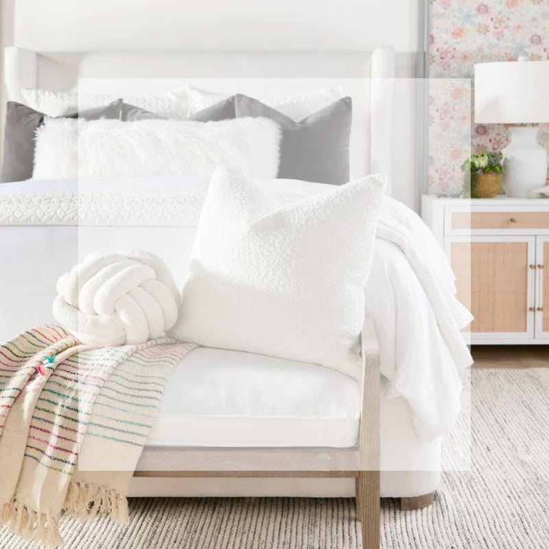Bench at foot of bed with white cushion and white pillows on top