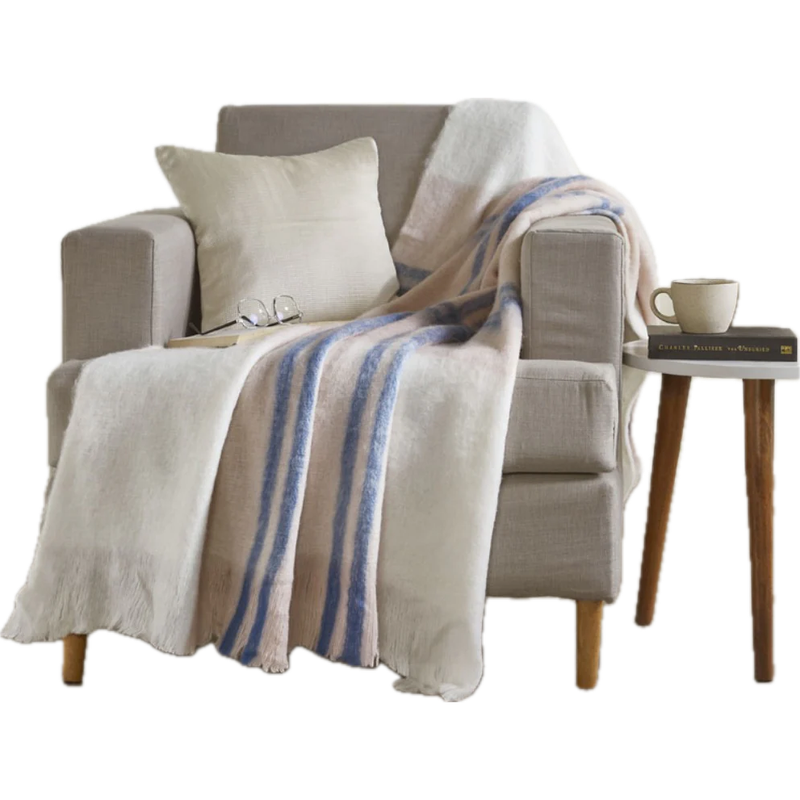 Cozy armchair with India's Heritage Ivy Striped Mohair Throw, pillow, glasses, a book; table holds a mug and more books.