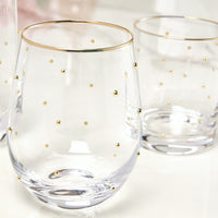 Clear stemless wine glasses with gold accents on a light background