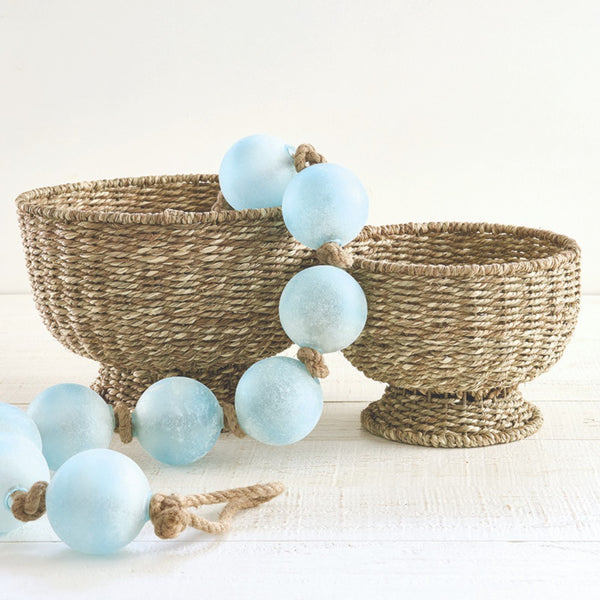 Decorative light blue beads on a rope with woven baskets on a white background