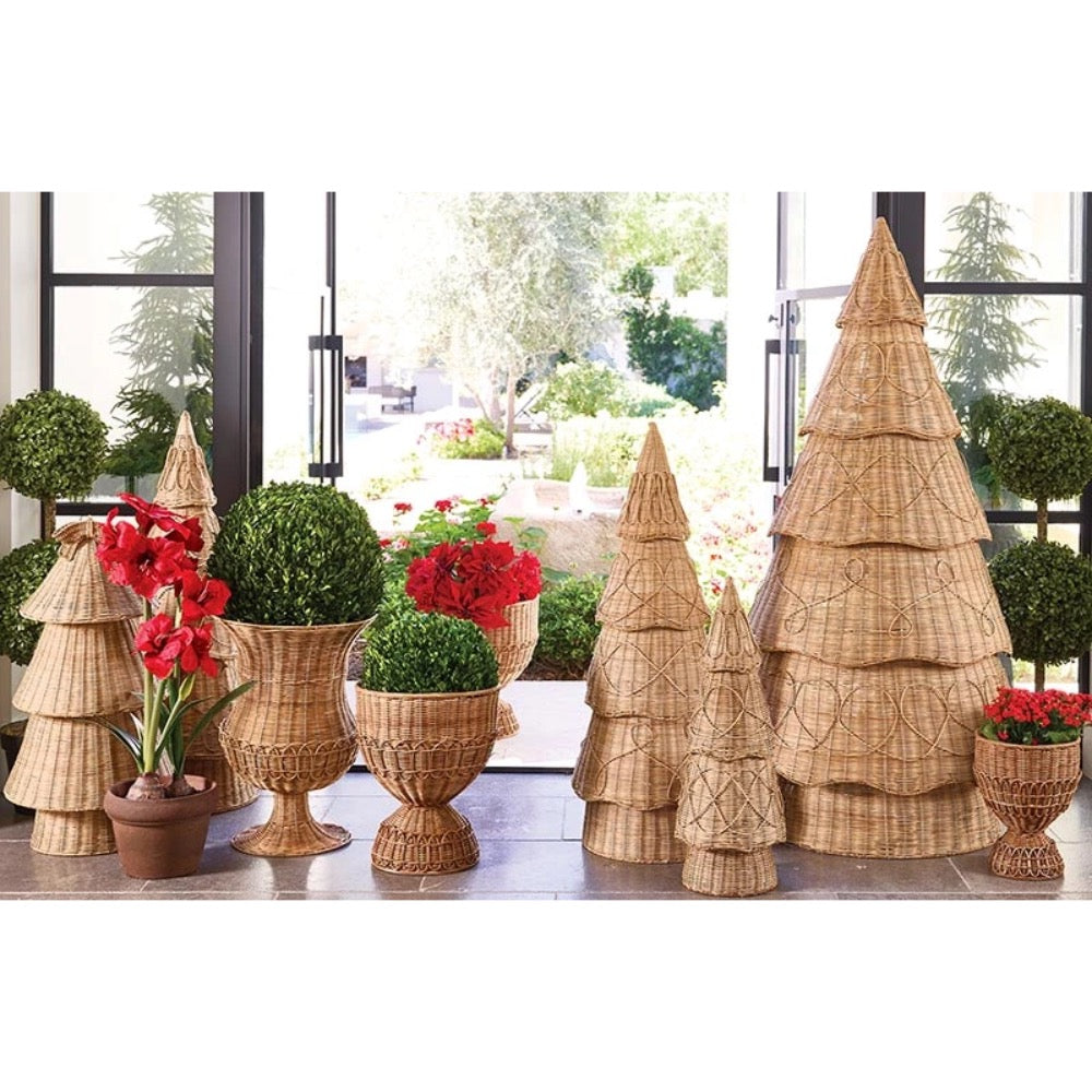A collection of decorative woven wicker holiday decorations displayed on a windowsill. The set includes three tiered cone Christmas tree stands in different sizes, three matching cone tree holders, several round woven planters with red flowers and green topiary bushes, and a small red flower planter.