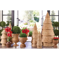 A collection of decorative woven wicker holiday decorations displayed on a windowsill. The set includes three tiered cone Christmas tree stands in different sizes, three matching cone tree holders, several round woven planters with red flowers and green topiary bushes, and a small red flower planter.