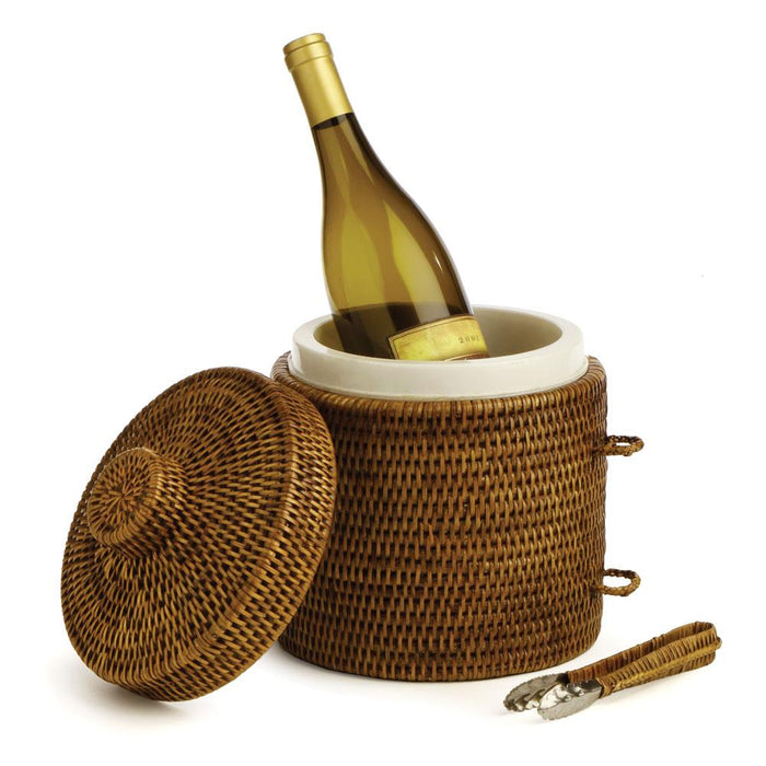 A woven rattan wine cooler with a matching lid, shown with a white ceramic insert holding a white wine bottle and a pair of metal tongs on a white background.