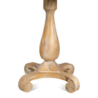 A close-up of a distressed light beige wooden table base with a turned central column and three scrolled feet, shown against a plain white background.