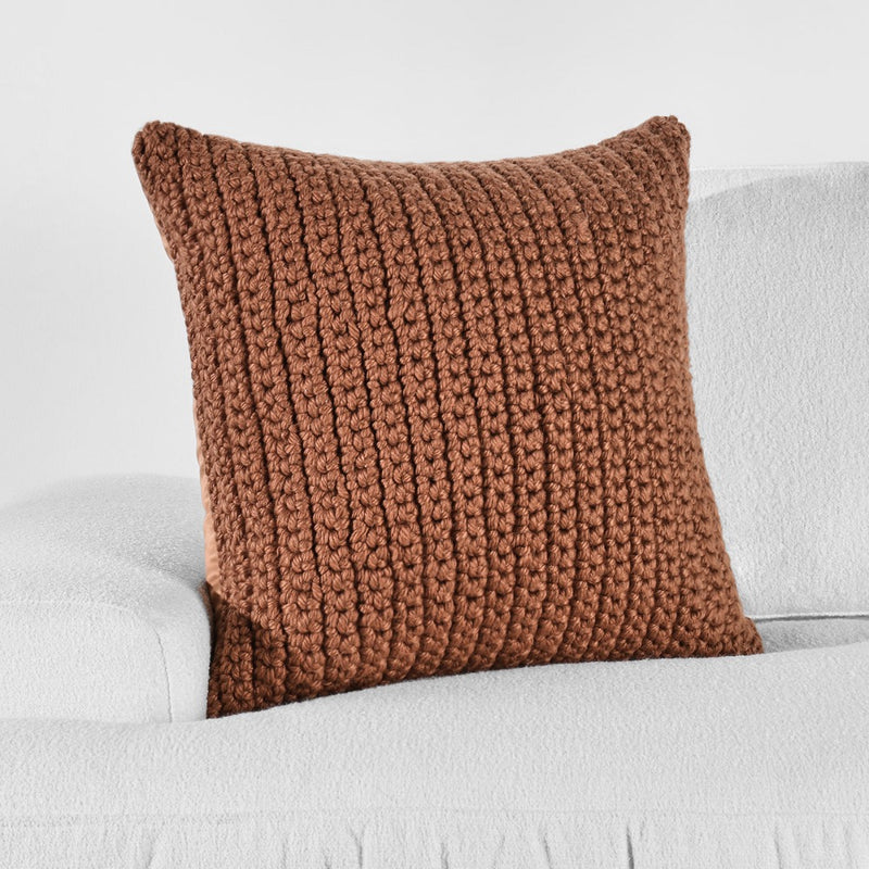 The Classic Home Outdoor Performance Prism Terracotta Pillow on a white sofa with a plain white background.