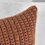 Close-up of Classic Home's Outdoor Performance Prism Terracotta Pillow on a white textured fabric background.
