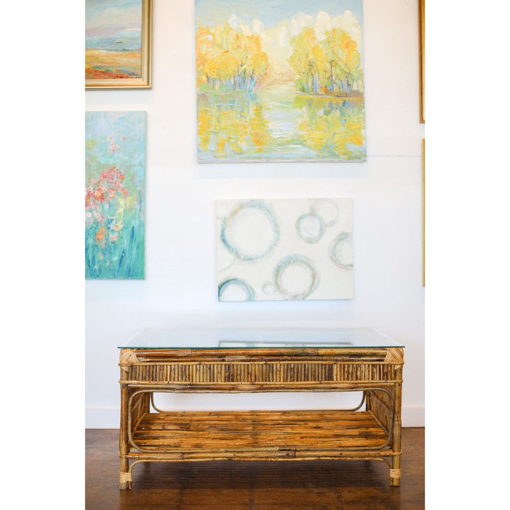 Rattan coffee table in front of a wall with framed artworks