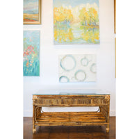 Rattan coffee table in front of a wall with framed artworks
