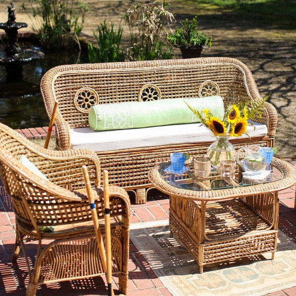 Wicker outdoor furniture set with a table and chairs in a garden setting.