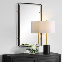 Decorative wall mirror with gold frame and lamp on a white wall.