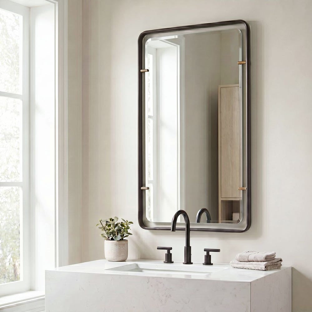 Modern bathroom with Uttermost Bronze Suspended Wall Mirror, black faucet, potted plant, and towels on marble sink.