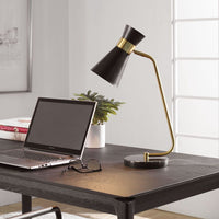 The Uttermost Black + Gold Desk Lamp with a black marble base sits on a modern dark wood desk beside a laptop.