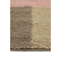 Close-up of a shaggy area rug showing a color-blocked pattern with a dusty pink section at the top, a taupe-brown section on the left, and a warm beige section on the right.