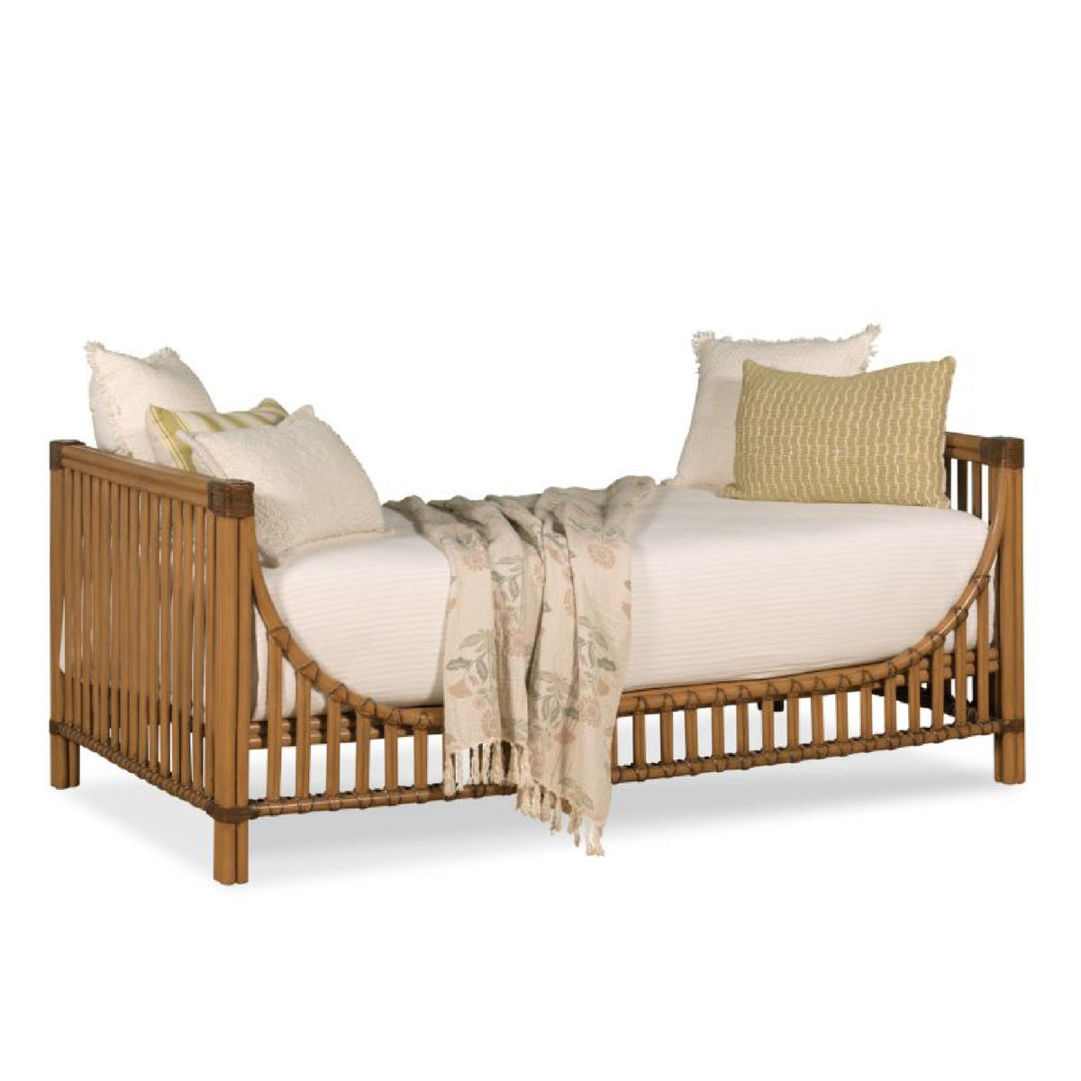 A natural bamboo daybed with a curved headboard and footboard, styled with cream-colored bedding, pillows, and a beige patterned throw blanket, set against a plain white background.