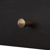 A close-up of a cylindrical cabinet knob with a speckled metallic bronze finish, mounted on a dark black wood drawer front.