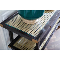 Close-up of a dark wood console table with a glass top and woven cane paneling, holding a teal ceramic vase.