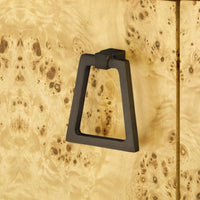 A matte black metal cabinet ring handle mounted on a light natural wood burl wood door.
