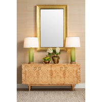 A mid-century modern sideboard cabinet with burl wood grain, flanked by two green table lamps with white drum shades, beneath a large gold-framed mirror on a beige textured wall.