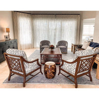 A modern living room with patterned chairs, sheer curtains, and a Kenian Pagoda Rattan + Bamboo Coffee Table.