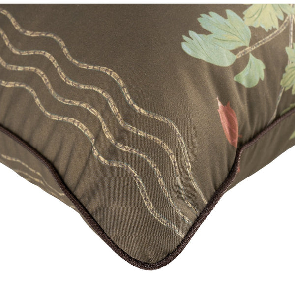 Close-up of a decorative throw pillow corner showing olive brown fabric with stitched wavy lines, dark brown piping, and a partial green leaf and muted red leaf print on a white background.