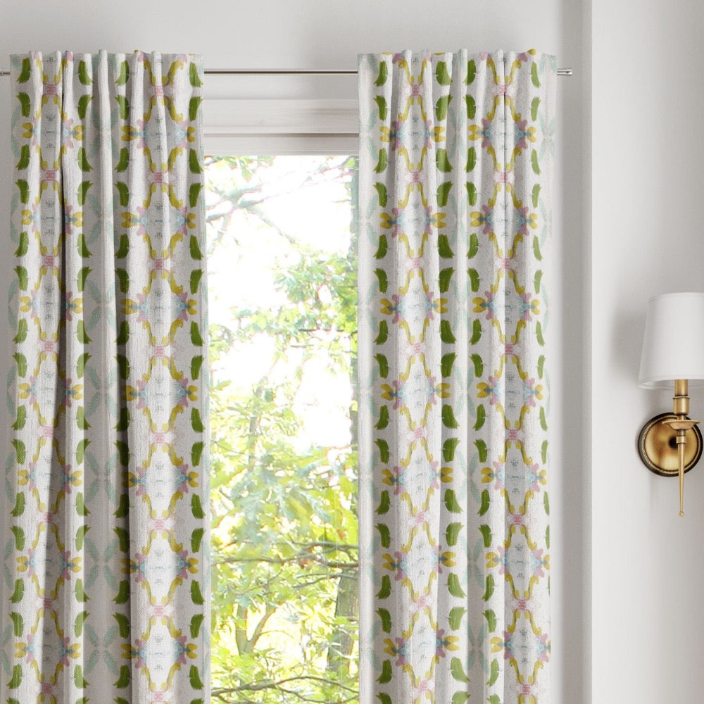 Dogwood Curtain Panels by Laura Park Designs in green and yellow frame a sunny window, highlighting the view outside.