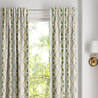 Dogwood Curtain Panels by Laura Park Designs in green and yellow frame a sunny window, highlighting the view outside.