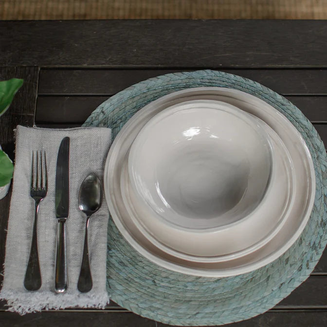 Place setting with white plates and Always Relish Double Line Cream Melamine Bowls (set of 4) on a blue placemat, accompanied by a fork, knife, and spoon next to a cloth napkin. The dishware is not only elegant but also dishwasher safe for easy cleanup.