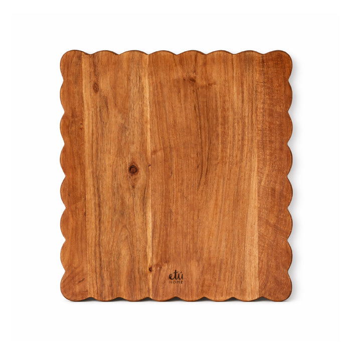 Wooden cutting board with scalloped edge on a white background