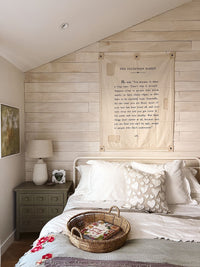 Bedroom with wooden wall paneling, bed with decorative pillows, and nightstand with lamp.