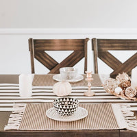 Dining table set with striped tablecloth, decorative bowls, and candles.