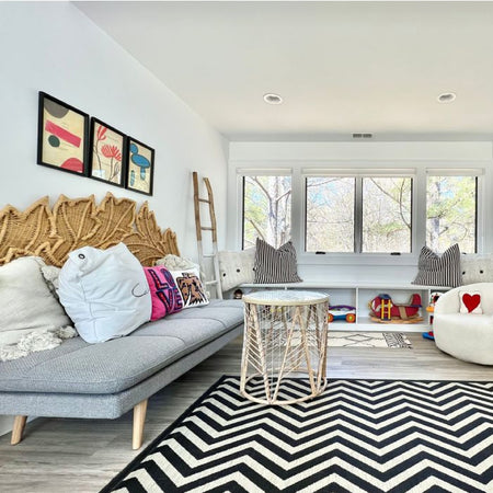 Kids playroom with unique playful art on the walls and a black and white rug.