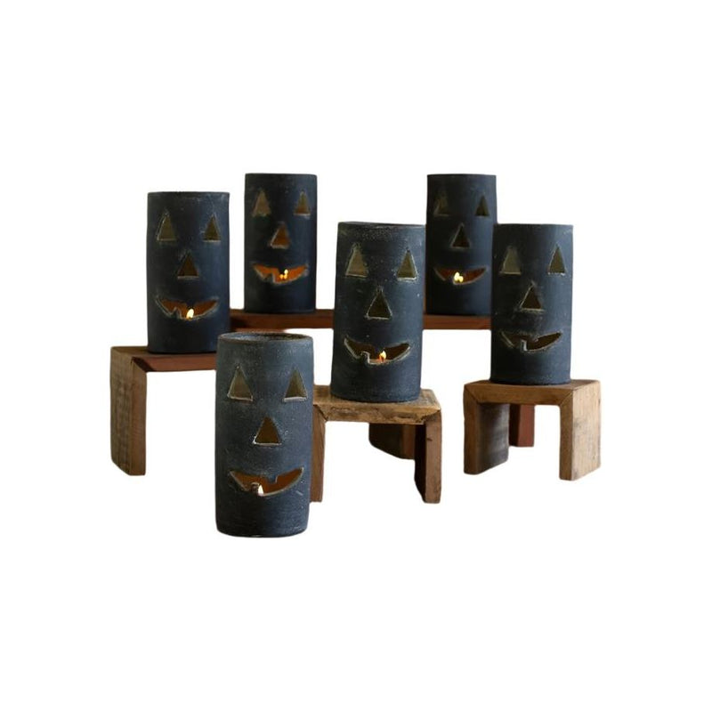 Six Black Clay Jack-O-Lanterns by Kalalou, each with a smiling face that embodies Halloween charm, are displayed on wooden stands.