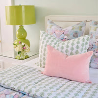Bedroom with floral bedding, pink pillow, and green lamp.