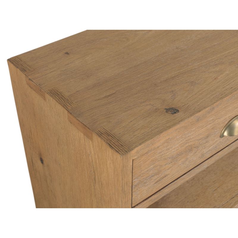 Close-up of a light oak wood console table showing the top surface, corner joinery, drawer front, and part of a brass pull handle against a white background.