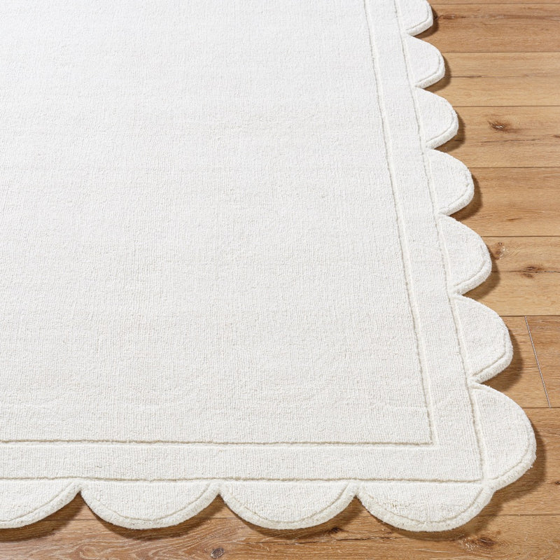 The wooden flooring is beautifully adorned with the Mystique Scalloped Wool Rug by Surya, featuring a hand-loomed design in white.