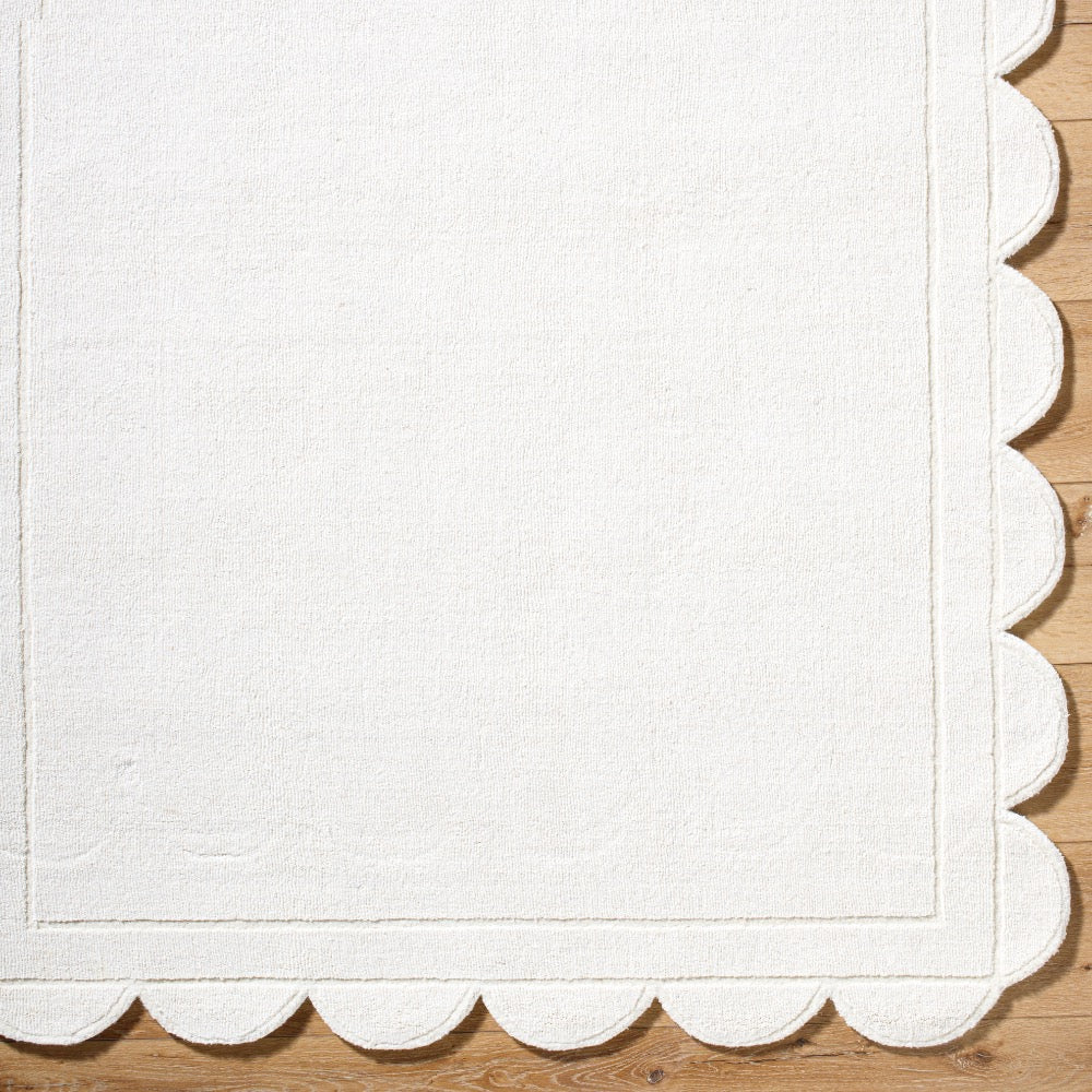The Mystique Scalloped Wool Rug by Surya elegantly adorns the wooden floor with its off-white premium design.