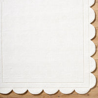 The Mystique Scalloped Wool Rug by Surya elegantly adorns the wooden floor with its off-white premium design.